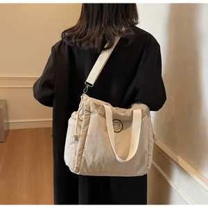 Vista laterale della borsa tote in tela bianco crema con coulisse e patch a orsetto