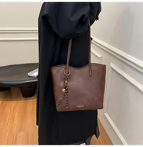 Detail of dark brown tote bag with fashion gold lettering and woven ball charm