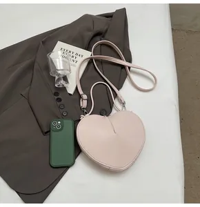 Detail view of pink heart-shaped handbag on a grey blazer with accessories