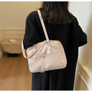 Dettaglio della borsa shopper rosa lucida con tasca frontale e scritta in rilievo elegante