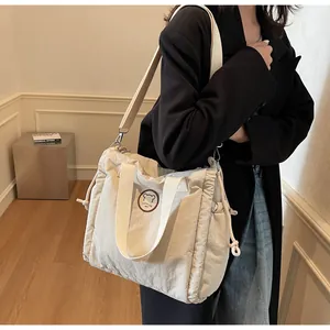 Dettaglio borsa a tracolla beige con logo orsetto e texture laterale a coulisse