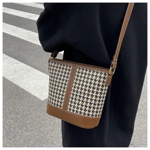 Detail of houndstooth bucket bag with brown leather trim and adjustable shoulder strap