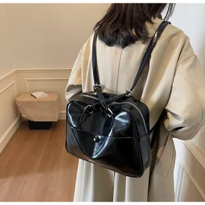 Dettaglio borsa tote nera in vernice con spallacci regolabili in stile minimalista
