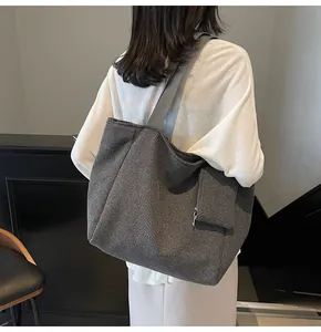 Detail view of large woven tote bag in grey plaid texture with wide shoulder strap