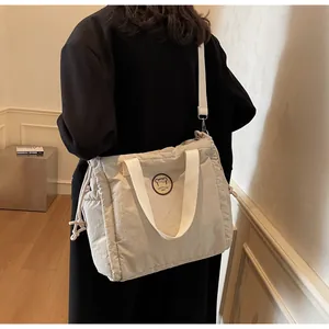 Dettaglio della borsa tote in tela beige con tracolla regolabile ed emblema di orsetto