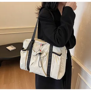Seitenansicht der beigen Nylon-Tragetasche mit Kordelzugtasche und Trikolore-Streifen