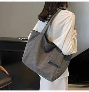 Detail of grey checkered tote bag showing wide shoulder strap and functional side zipper