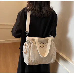 Vista dettagliata di una borsa a tracolla beige con tracolla larga su cappotto nero