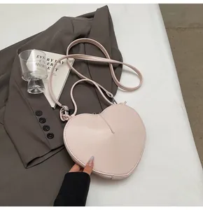 Detail of light pink heart-shaped leather bag with double straps and minimalist styling