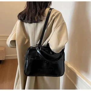 Dettaglio della borsa a tracolla in pelle lucida nera con trench coat kaki corto