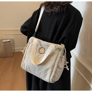 Vista dettagliata della borsa tote in nylon crema con coulisse e toppa con orsetto ricamato