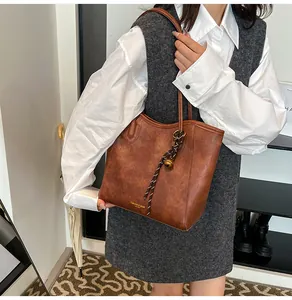 Detail of vintage brown tote bag with matte PU texture and golden tassel charm