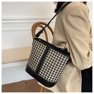 Detail of houndstooth bucket bag with black leather trim and gold metal hardware