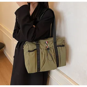 Detail der olivgrünen Nylontasche mit schwarzem Webgurt und praktischer Kordelzugtasche