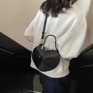 Asymmetric heart-shaped black crossbody bag with silver zippers and adjustable strap