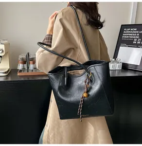 Detailed view of a black leather tote bag with gold hardware and striped inner lining