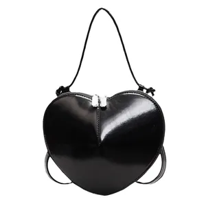 Glossy black heart-shaped crossbody bag with silver zippers and reflective leather finish