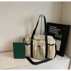Detail der beigen Nylon-Reisetasche mit Kordelzugtasche vorne und verstellbarem Gurt