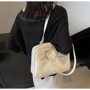 Dettaglio di una borsa a spalla in pelle bianco crema con trama a rilievo e zip metallica
