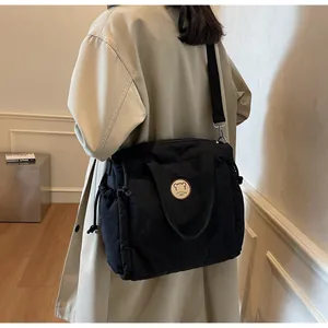 Dettaglio della borsa tote in nylon nero con toppa a orsetto e coulisse sui lati