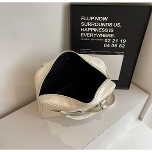 Vista dall'alto della borsa bowling crema minimalista con manici tondi su marmo