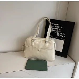 Dettaglio di una borsa tote color bianco panna in pelle PU con tasca e logo in rilievo