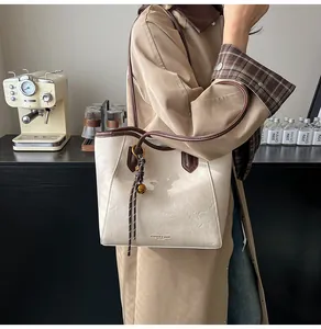Detail of minimalist tote bag with dark brown trim and woven bell charm accessory