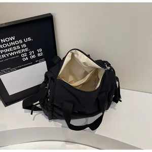 Dettaglio della borsa a tracolla nera che mostra la fodera beige e lo spazio interno