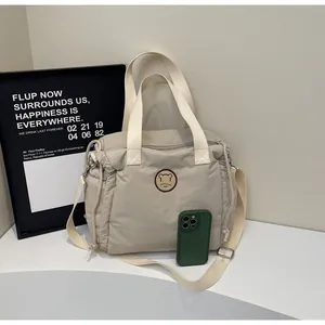 Dettaglio borsa tote in nylon crema con logo orso e tracolla regolabile in tessuto