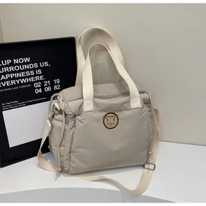 Dettaglio della borsa in nylon grigio con patch orso e manici in tessuto resistenti
