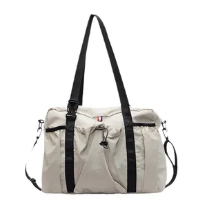 Große beige Nylon-Tragetasche mit schwarzen Riemen und Kordelzug im minimalistischen Stil