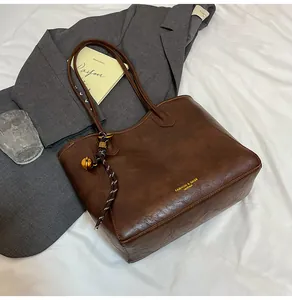Close-up of vintage brown leather tote bag with gold lettering and decorative pendants
