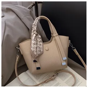 Detail of beige leather bucket bag with houndstooth silk scarf and silver metal buckle