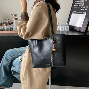 Fashionable black faux leather tote bag with braided strap detail on a trench coat model