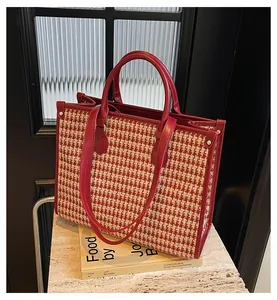 Detail of red houndstooth tweed tote bag featuring faux leather handles and metal rivets