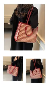 Macro shot of large red houndstooth tote bag featuring leather handles and shoulder strap