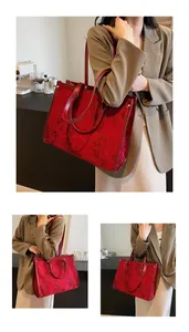 Detailed close-up of large red tote bag with floral embroidery and leather handles