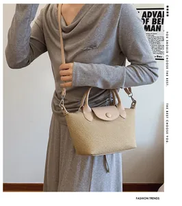 Close-up of small straw woven crossbody bag with leather handles and flap closure