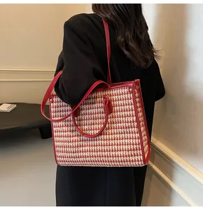 Detail of red houndstooth tote bag with leather straps on a black coat outfit