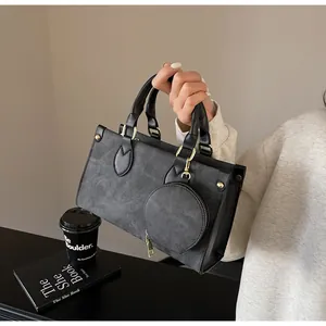Detail of dark gray tote bag with matte texture and removable round zipper coin purse charm