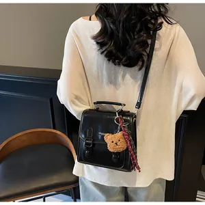 Vista trasera detallada del bolso bandolera negro con colgante de oso y pañuelo