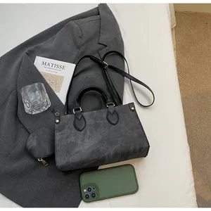 Detail of dark grey textured tote bag and mini pouch set over a stylish grey blazer