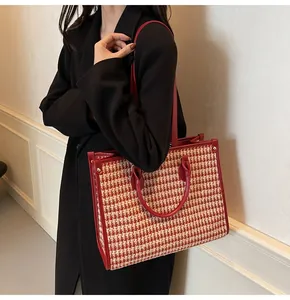Detail of red and white houndstooth pattern tote with smooth leather straps and rivet accents