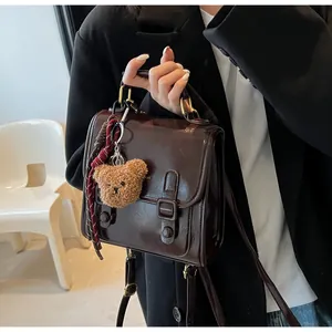 Detalle del bolso de hombro vintage marrón oscuro en ecocuero con un llavero de oso de peluche