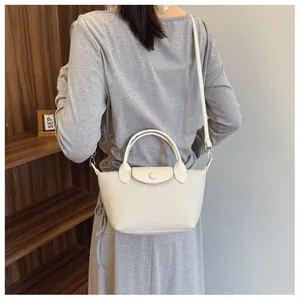 Detail shot of beige woven texture shoulder bag with leather flap and snap closure