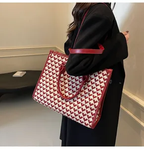 Detailed close-up of a red and white tote bag with heart patterns and leather straps
