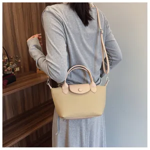Close-up of woven straw texture with beige leather handle and magnetic flap closure