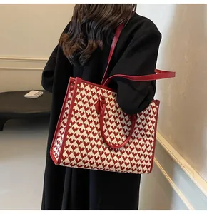 Detail showing red and white heart-patterned tote bag with premium leather straps