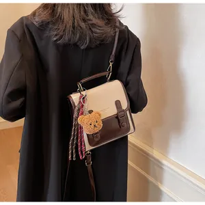 Vista trasera de modelo con bolso bandolera de cuero bicolor vintage y colgante de oso