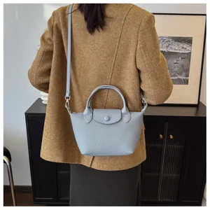 Detail showing the woven texture of the light blue crossbody dumpling bag on a model